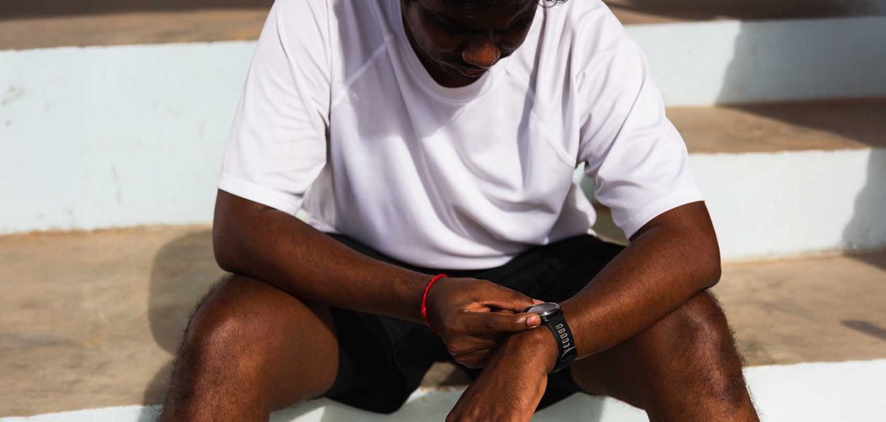 black teenage boy checking his fitbit which provides sleep data