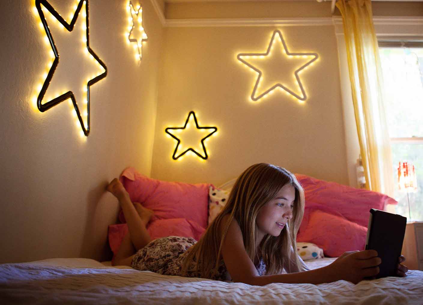 young girl on mobile device cell phone social media in bedroom decorated by stars