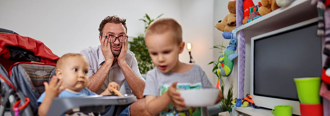 stressed dad with 2 kids in messy living room