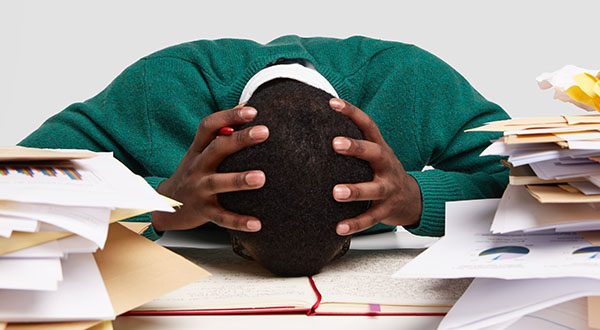 workaholic man with head down on desk around paperwork