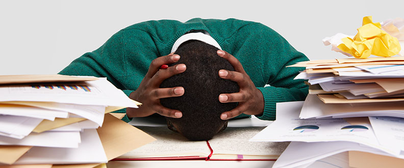 workaholic man with head down on desk around paperwork
