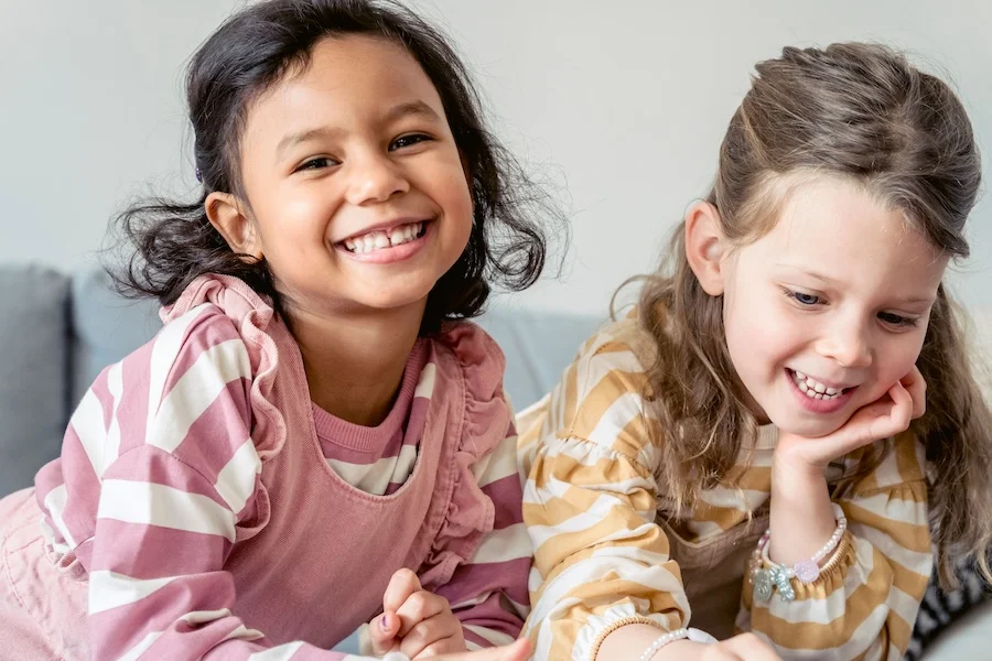 Two girls smiling on a couch.