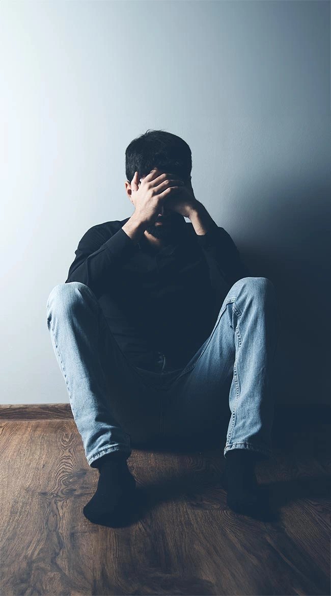 PrasadCounselingAndTraining-Man-sitting-on-the-floor-with-hands-covering-face Man sitting on the floor with hands covering his face
